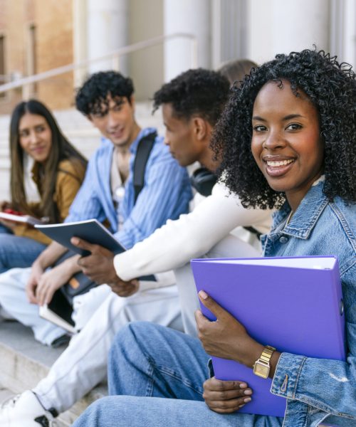 Multiracial student group relaxing and talking on campus outdoor stairs, embodying youth, friendship, and education