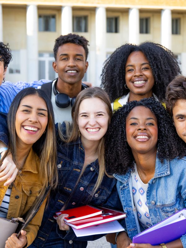 Happy diverse students posing together on university campus, embracing friendship and education, building community with their classmates